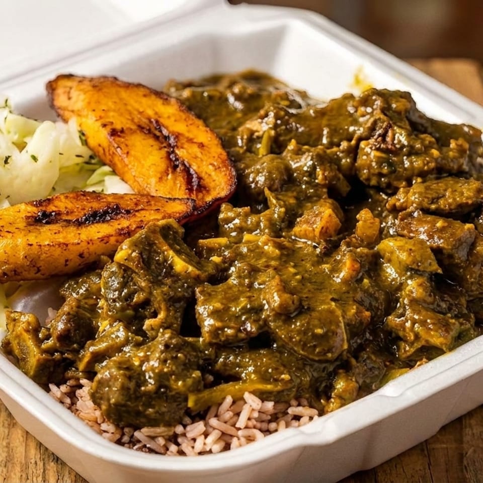 Curried goat with rice, cabbage, and plantains in a white takeout container on a wooden table.